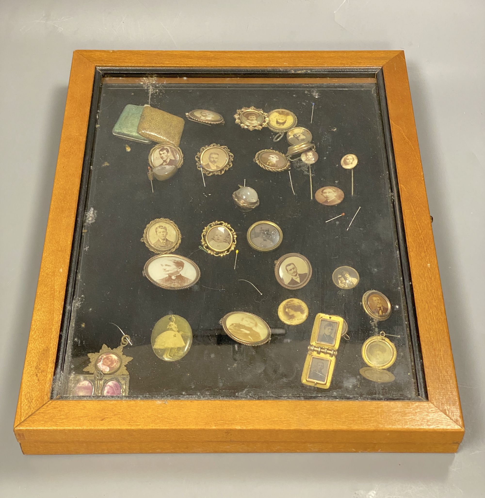 A collection of gilt metal stick pins, brooches, etc. with inset photographic miniatures in glazed case